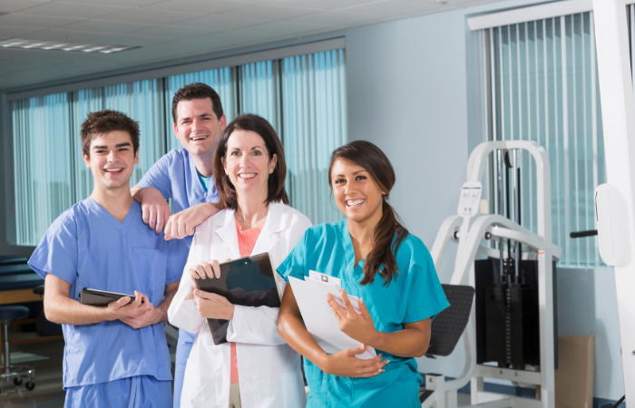 Four physical therapists in front of equipment.